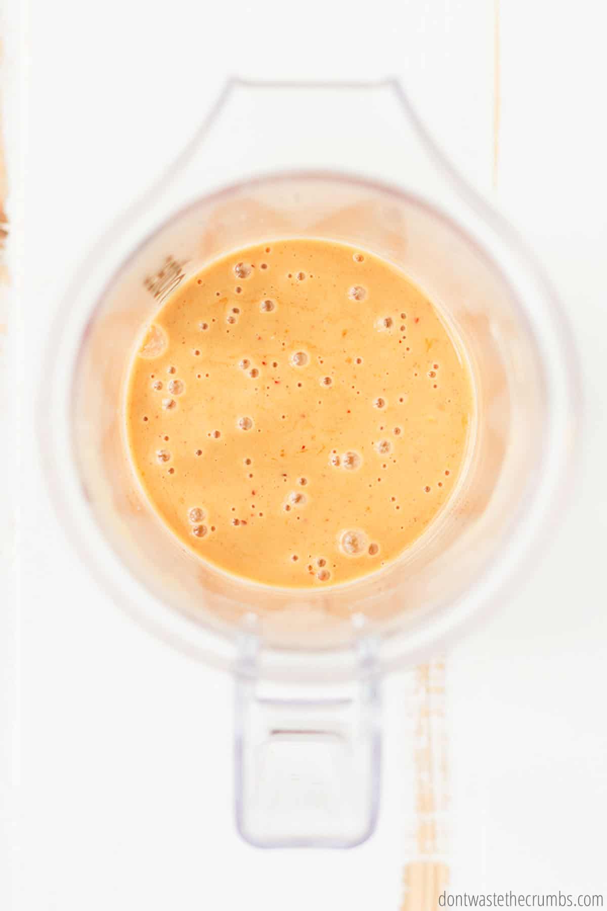 Thai peanut sauce is blended to a smooth and liquid-like consistency in the blender, pureed to a golden brown color.