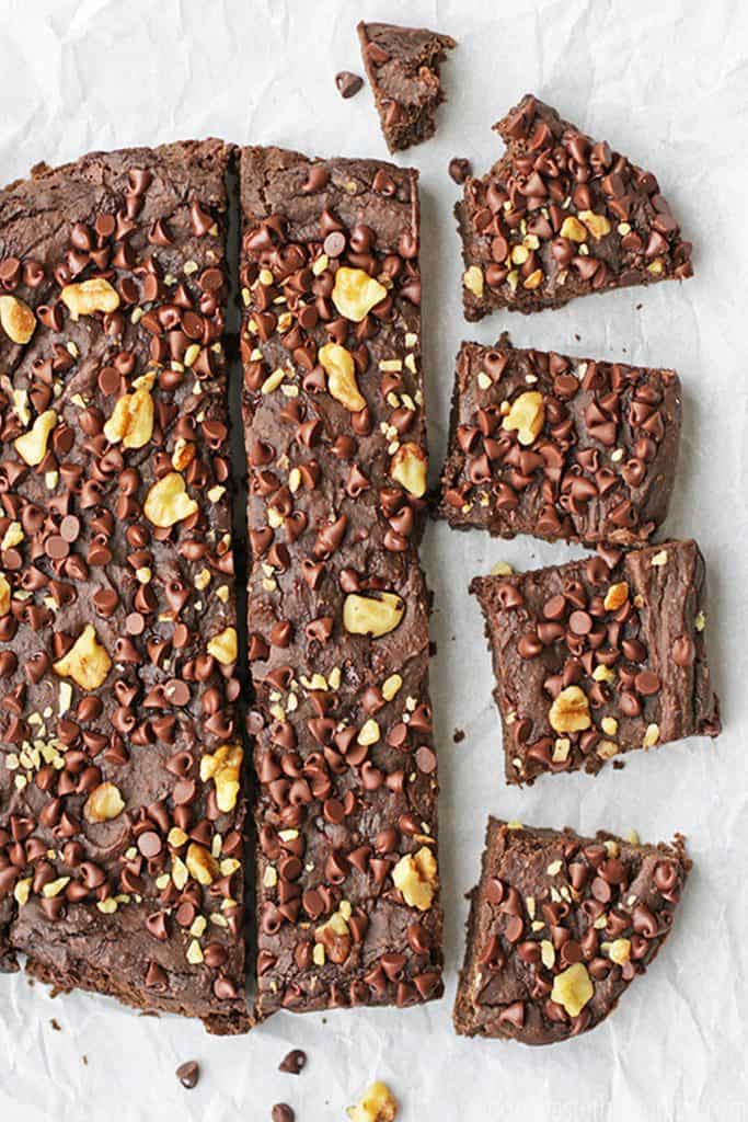 Freshly baked black bean brownies cut into squares, topped with chocolate chips and walnuts.