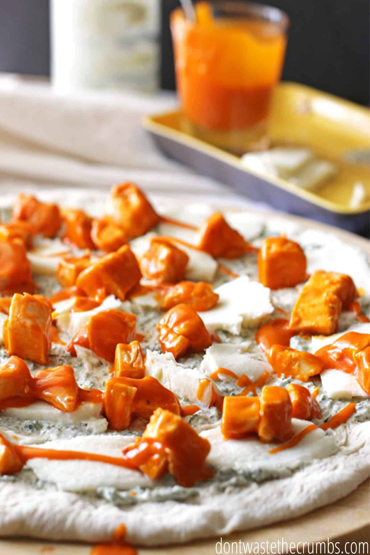 Freshly rolled pizza dough with mozzarella cheese, blue cheese dressing, cubed chicken slathered in buffalo sauce. Ready to be baked in the oven!