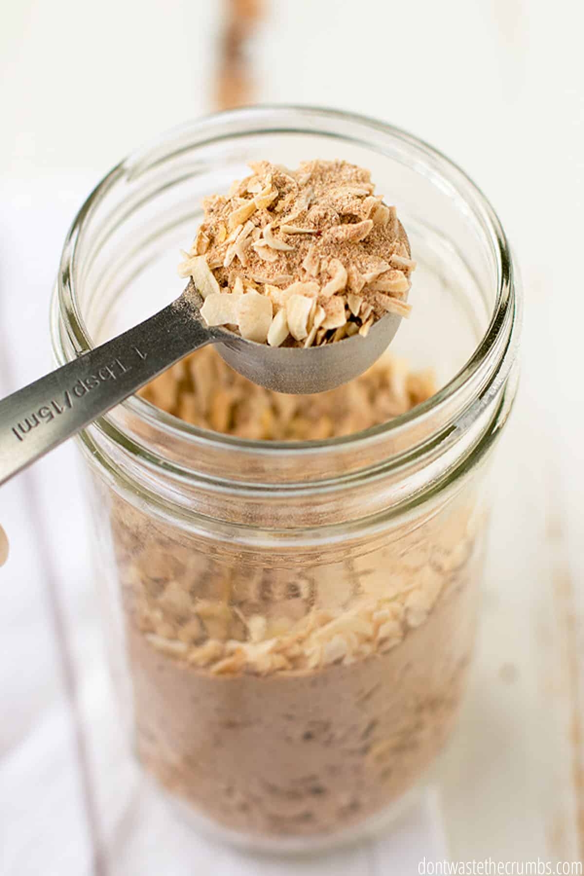 Glass jar of dry onion soup mix with a full measuring spoon