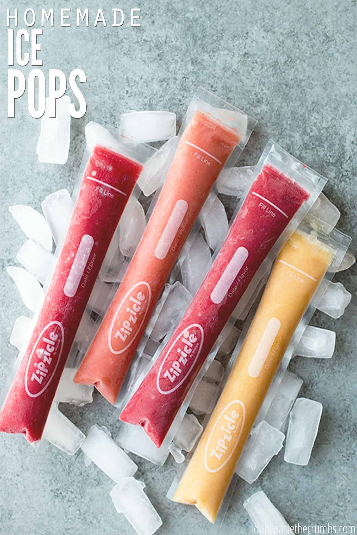 Four homemade ice pops of various flavors lying on scattered ice cubes