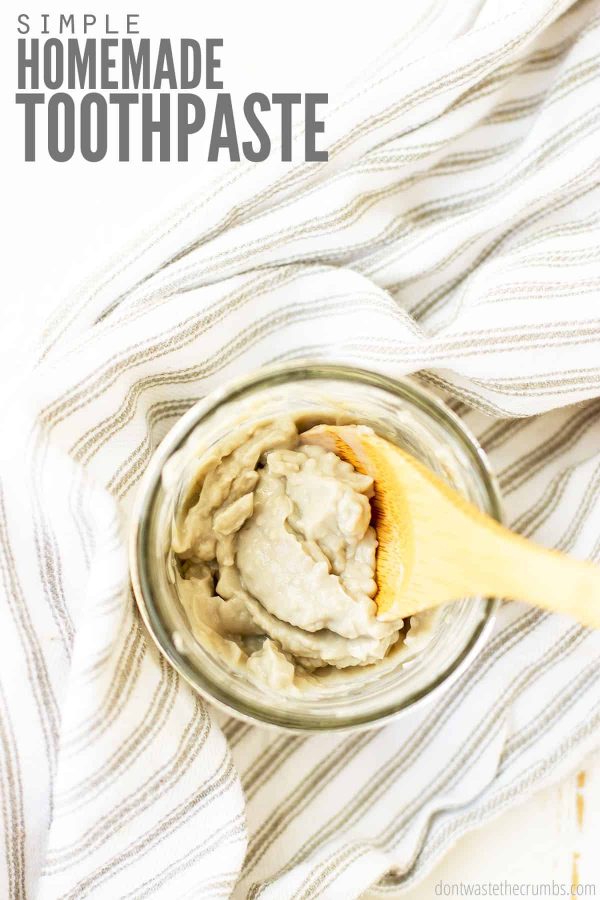 Homemade toothpaste in a small glass jar with wooden spoon. Text overlay: Simple Homemade Toothpaste