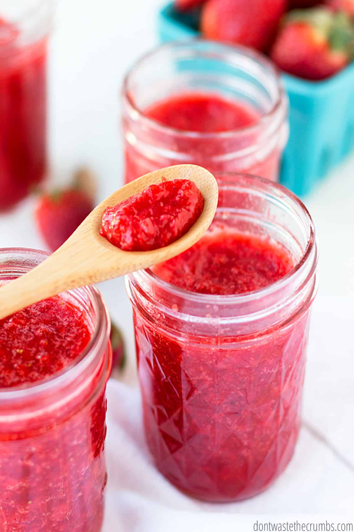Three jars are filled with strawberry jam.