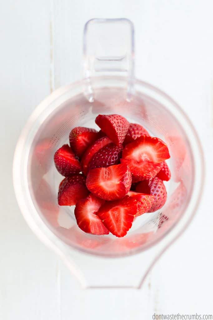 A blender is filled with cut strawberries.