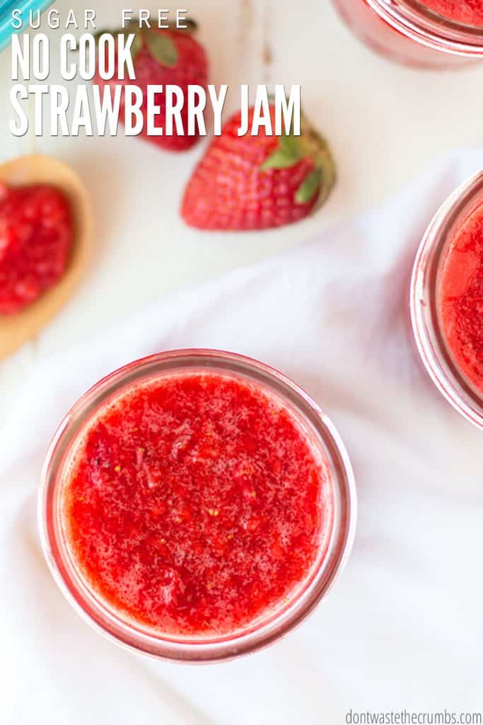 A jar, viewed from above, is filled with bright red strawberry jam.