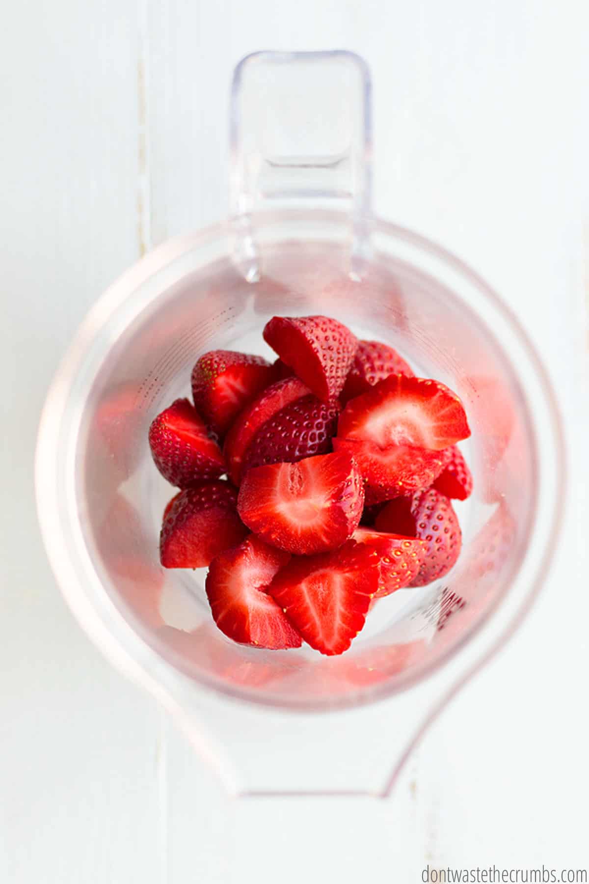 A blender is filled with cut strawberries.