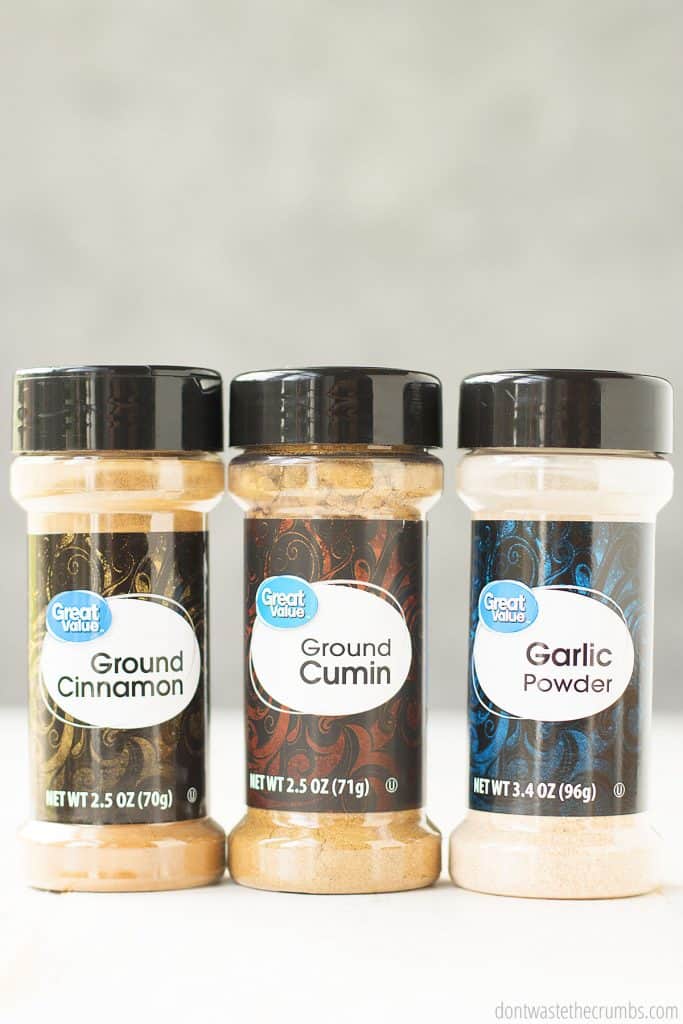 Three bottles of conventional spice, ground cinnamon, ground cumin, and garlic powder. Conventional spices can contain any number of contaminants, so we opt for organic spices.