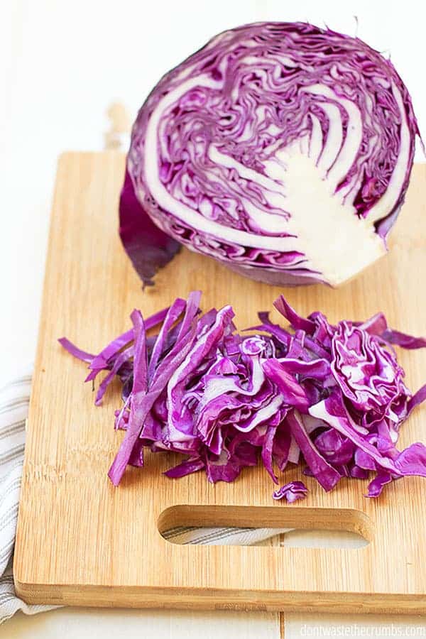 Half of cabbage and shredded cabbage on a cutting board