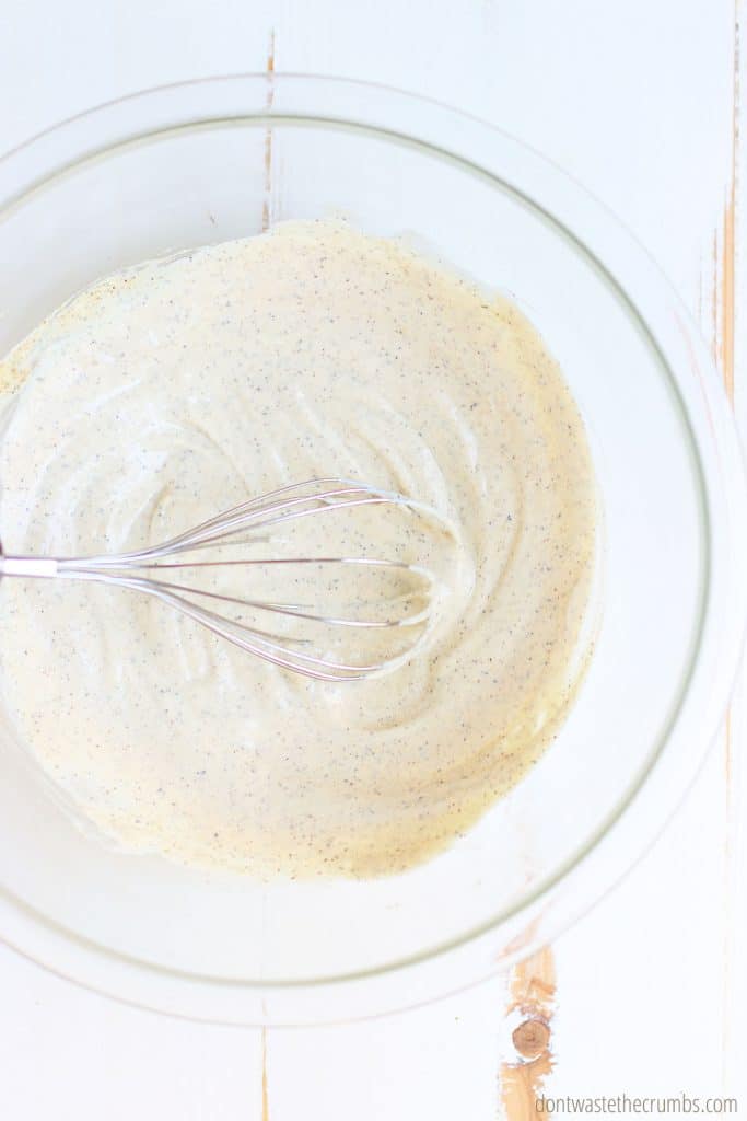Creamy coleslaw dressing mixed with a whisk before the cabbage and carrots are added.