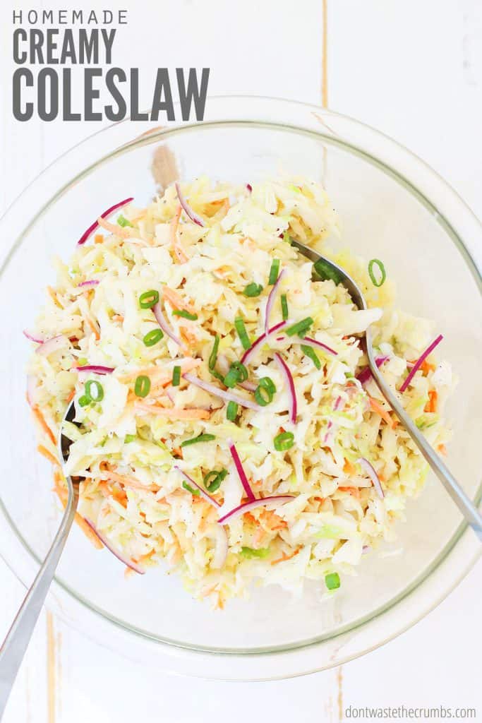 Clear glass bowl with homemade creamy coleslaw, finished with green onions. Text overlay reads "Homemade Creamy Coleslaw."