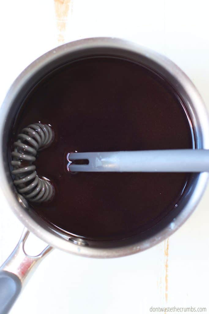 The first step to making elderberry gummies is to put your elderberry syrup into a small saucepan. There is a whisk in the pan as well.
