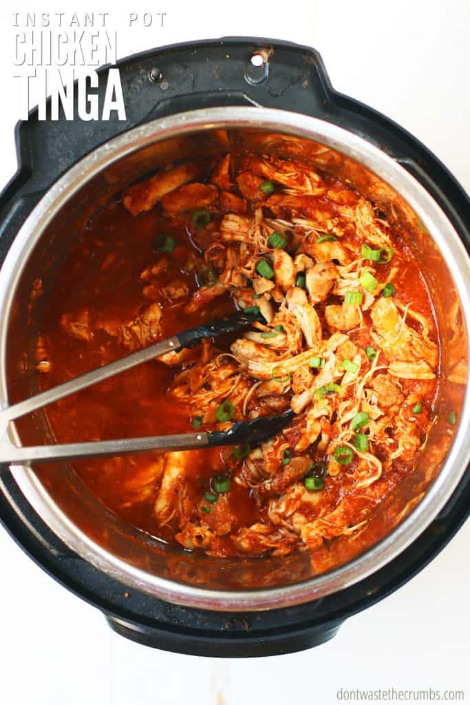 Freshly cooked chicken tinga in an instant pot finished with sliced green onions. The text overlay reads 'Instant Pot Chicken Tinga.'