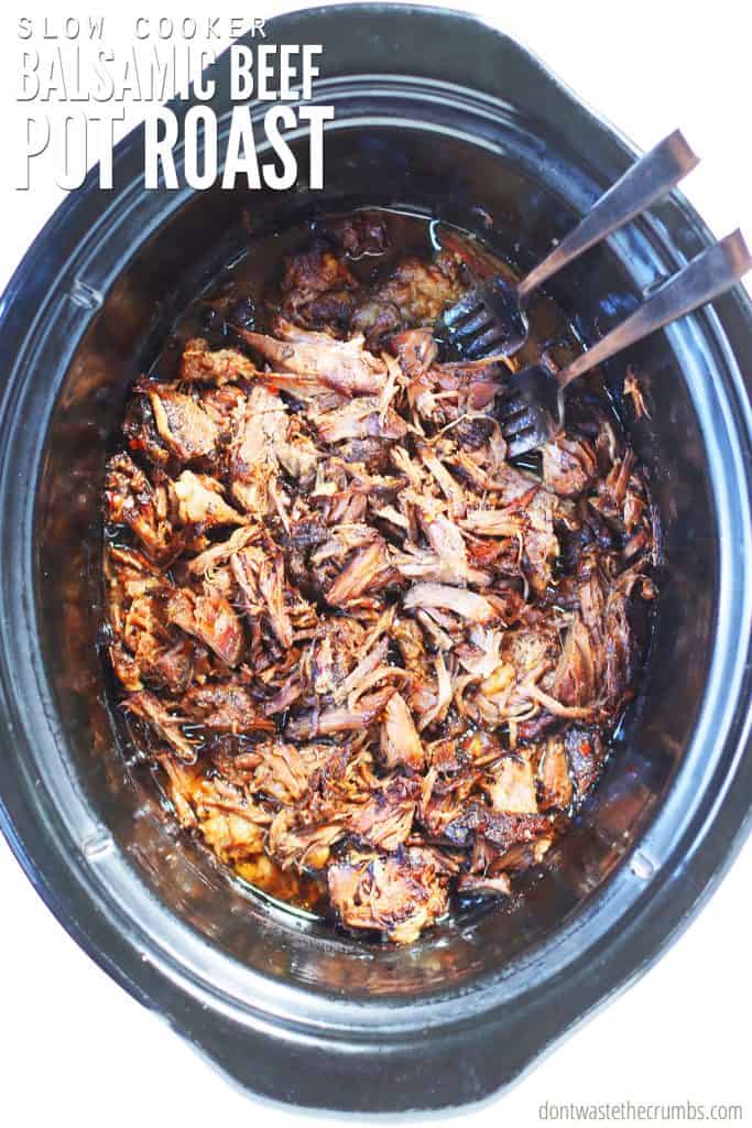 Slow Cooker Beef Pot Roast with balsamic sauce cooks in an oval slow cooker. The text overlay reads, 'Slow Cooker Balsamic Beef Pot Roast.'