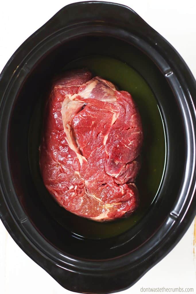 This raw chuck roast is in the slow cooker ready to be cooked for Mississippi pot roast!