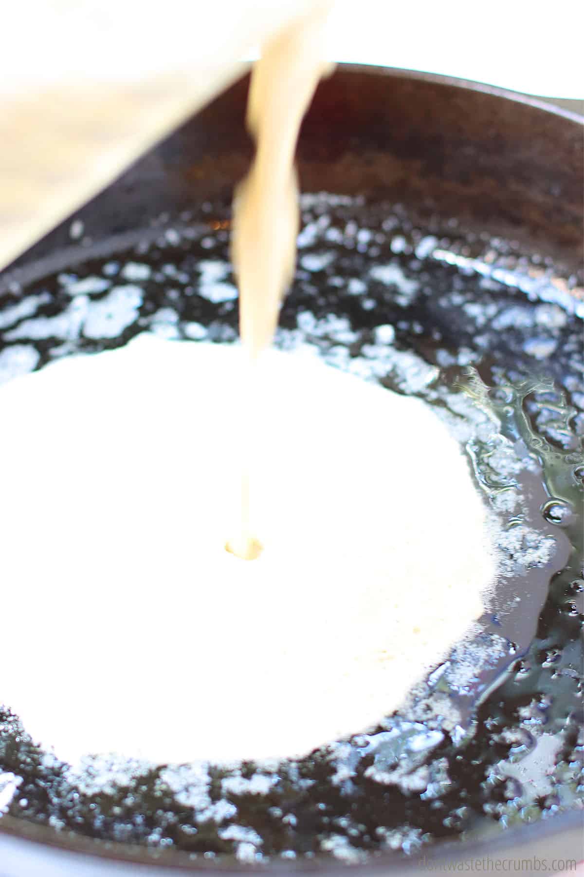 Pour the cornbread batter into the hot, greased cast iron skillet