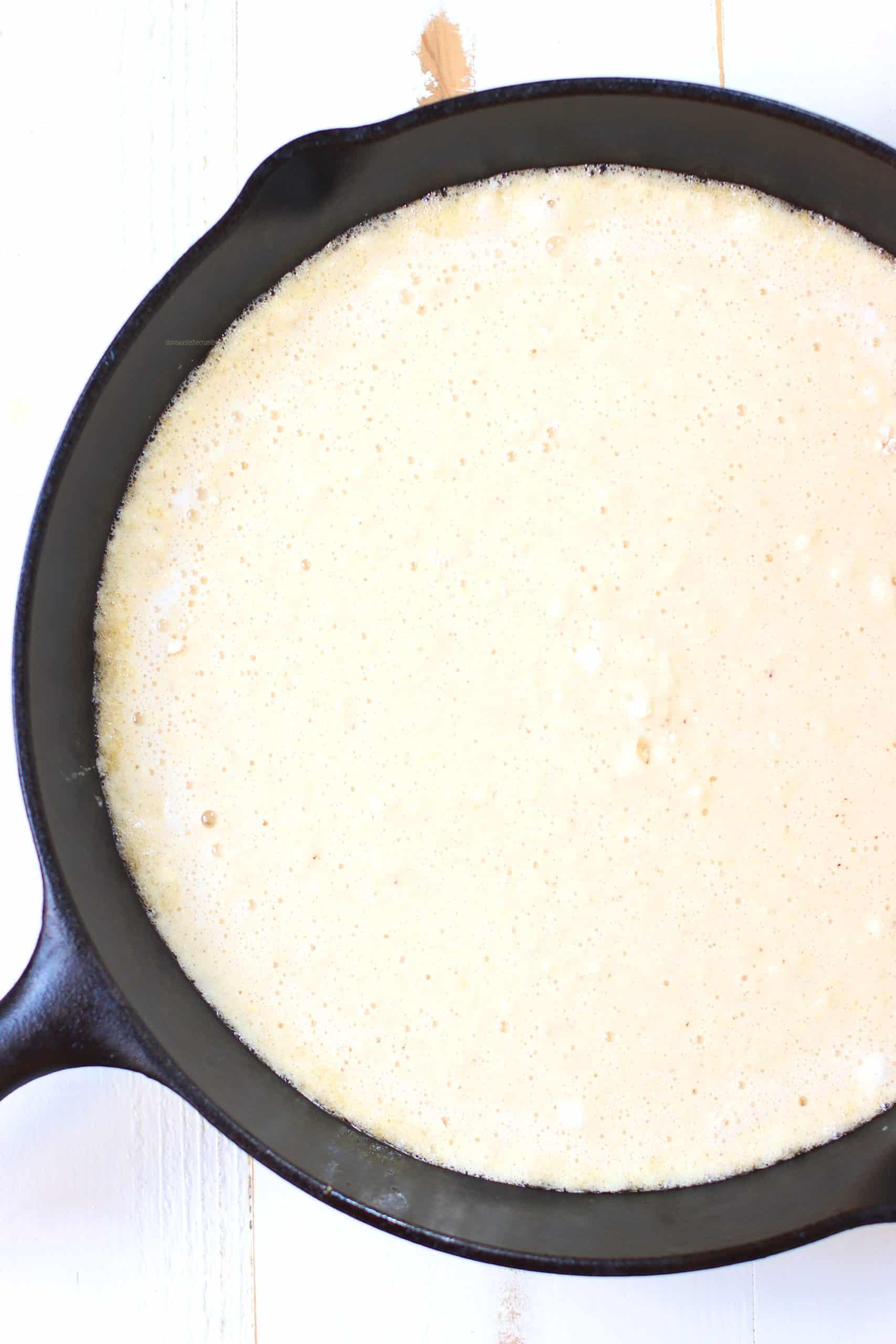 Cornbread batter cooking in a hot cast iron skillet
