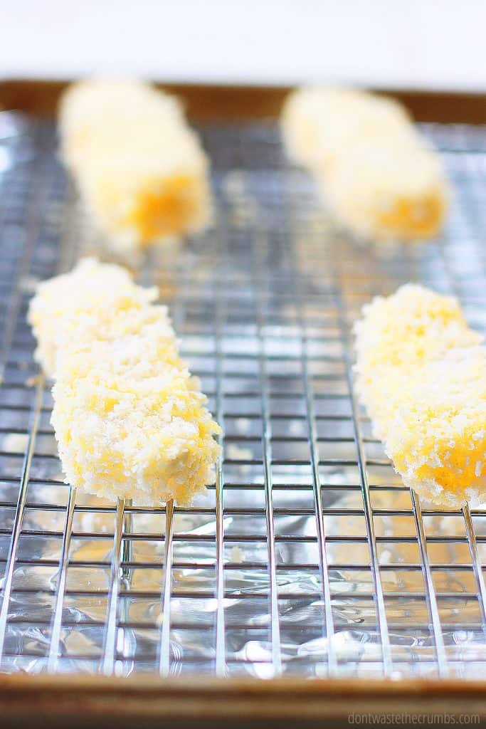 Perfectly panko breaded homemade fish sticks placed on a wire rack for baking. 