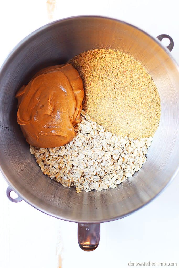 Peanut butter, rolled oats, and flax seed are in a large bowl ready to be mixed together.