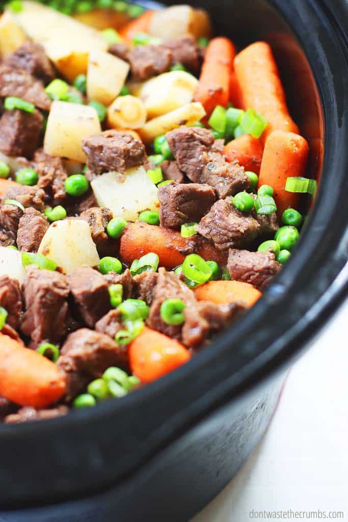 Slow cooker beef stew is all done! This is an up close view of cut beef, parsnips, turnips, carrots, and peas in the crock pot.