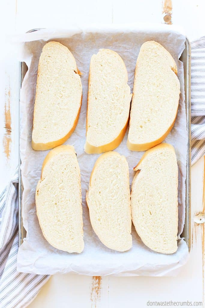 6 slices of sourdough bread on a baking pan with parchment paper. This is an easy crostini recipe!