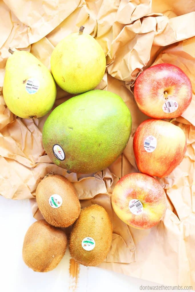 A mango, 2 pears, 3 apples, and 3 kiwis are laid out on a table.