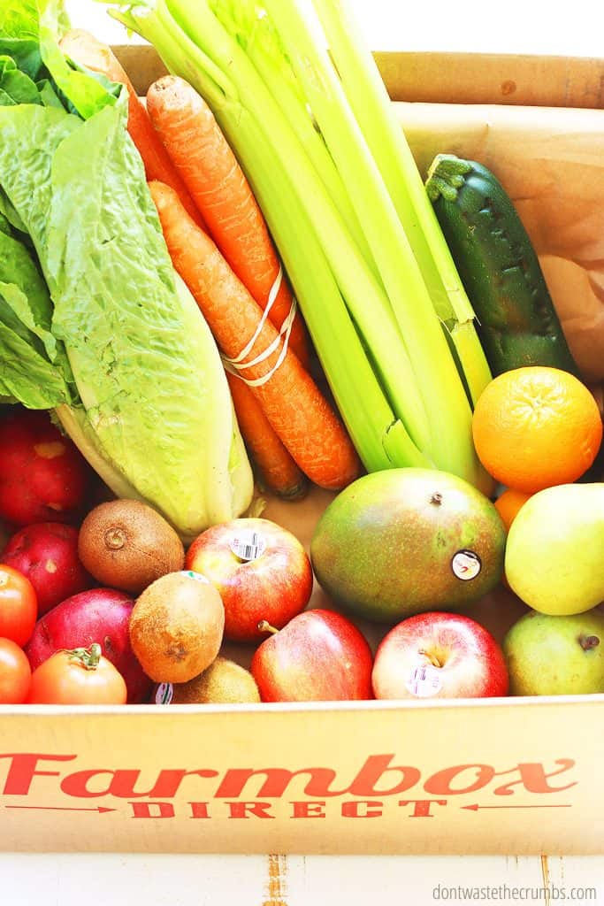 Lettuce, carrots, celery, cucumber, oranges,, kiwi, potatoes, mango, zucchini, and tomatoes are in a Farmbox Direct box.