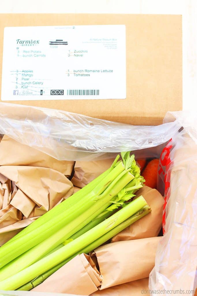 This is my Farmbox Direct review. Pictured is a box with the Farmbox Direct logo and list of produce that are in the box. There is a stock of celery being unboxed.