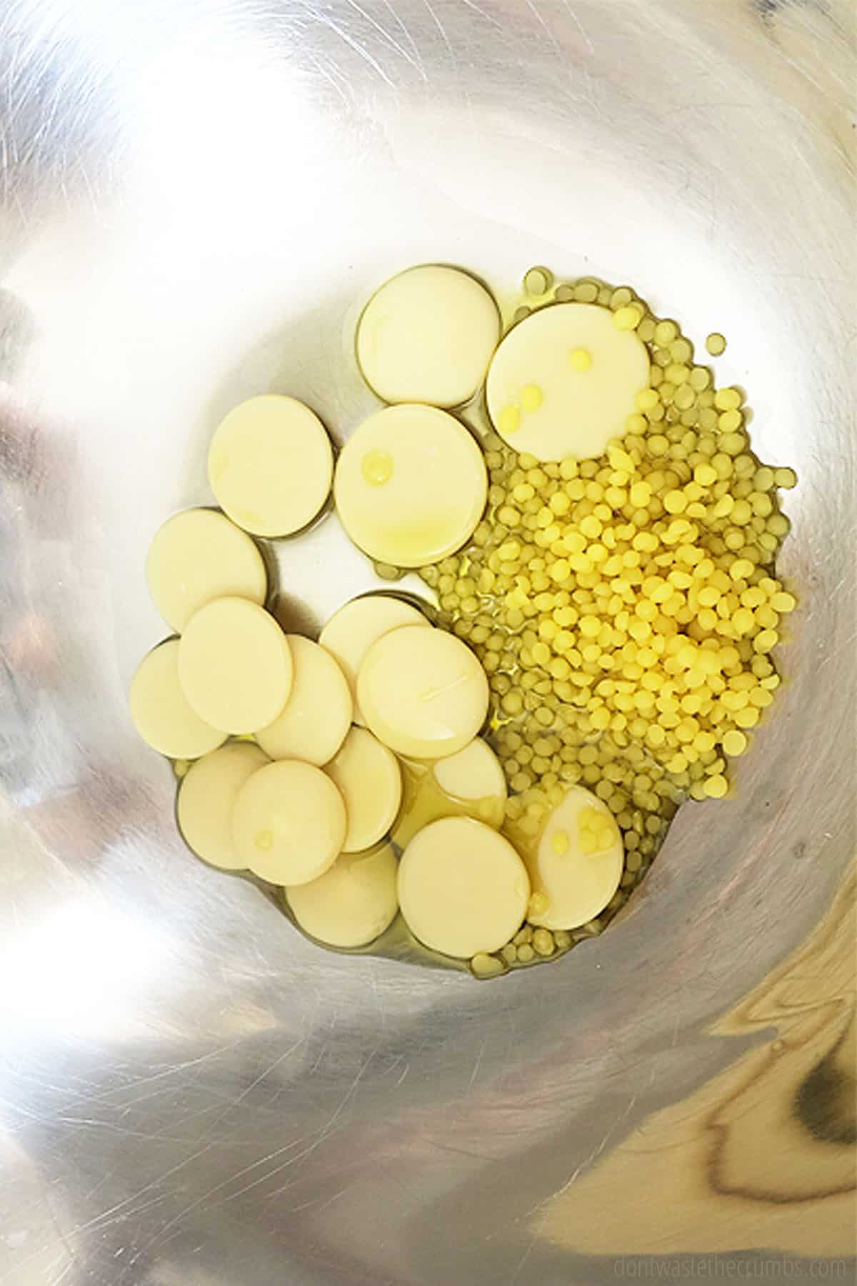 Beeswax, cocoa butter and olive oil in a stainless steel bowl.