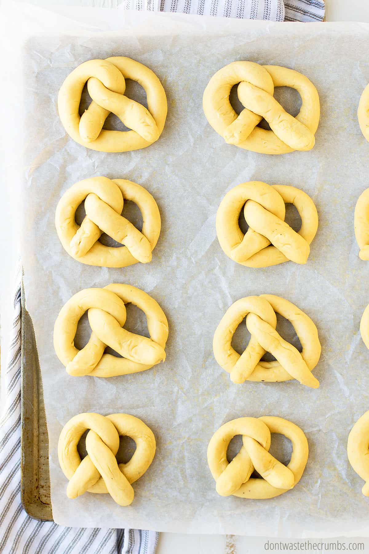 Soft pretzels on a baking sheet with parchment paper, ready to be baked.