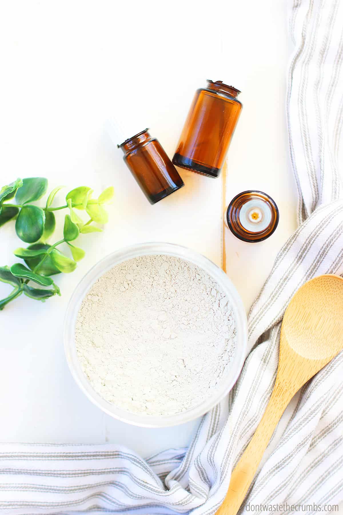 You'll need essential oils, bentonite clay, salt, sweetener, water and a wooden spoon to make your homemade remineralizing toothpaste.