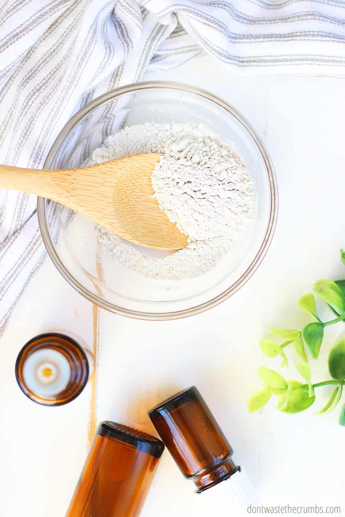 Bentonite clay in a glass bowl, spooned with a wooden spoon. 