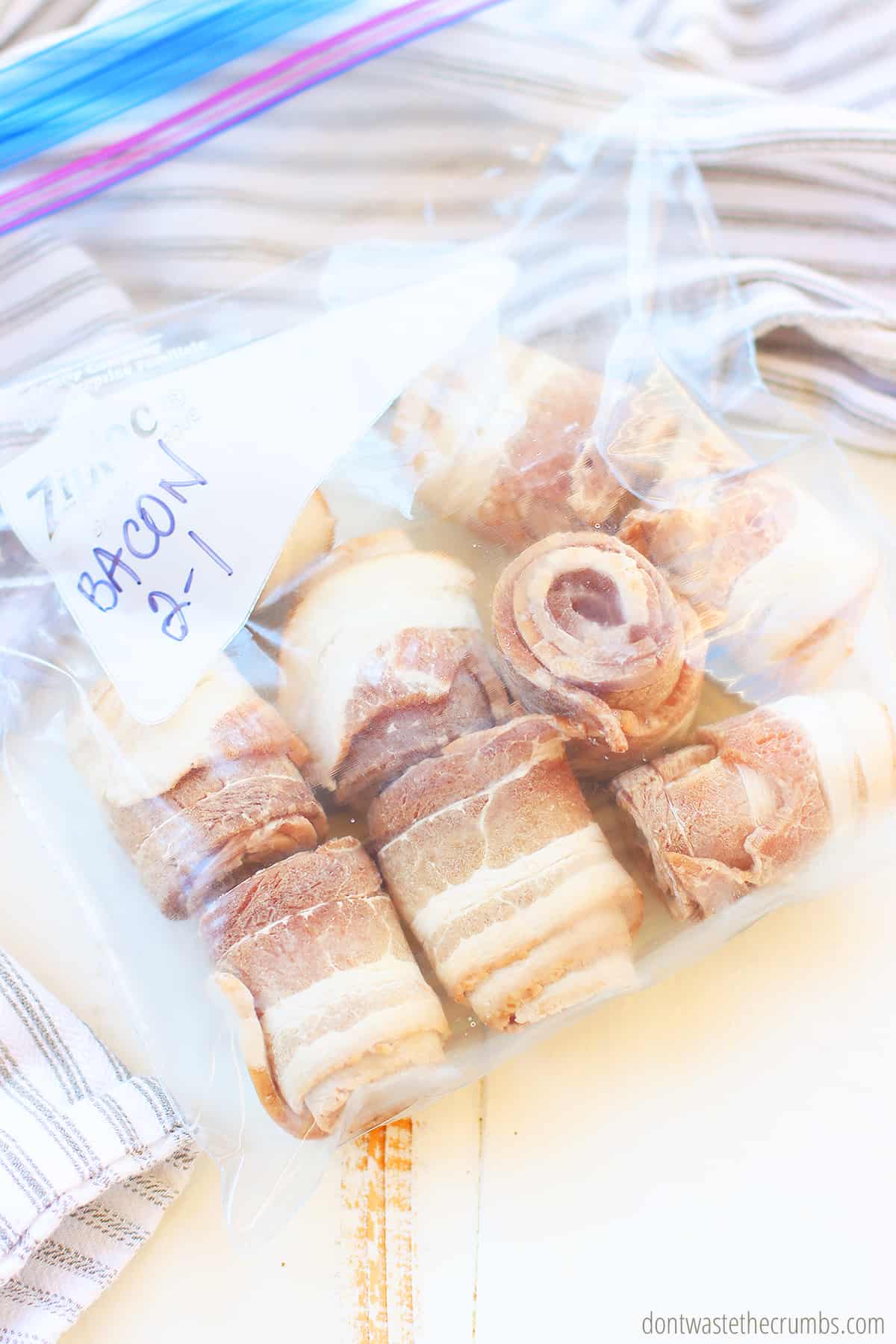 Marked freezer bag full of rolled and frozen bacon slices. 