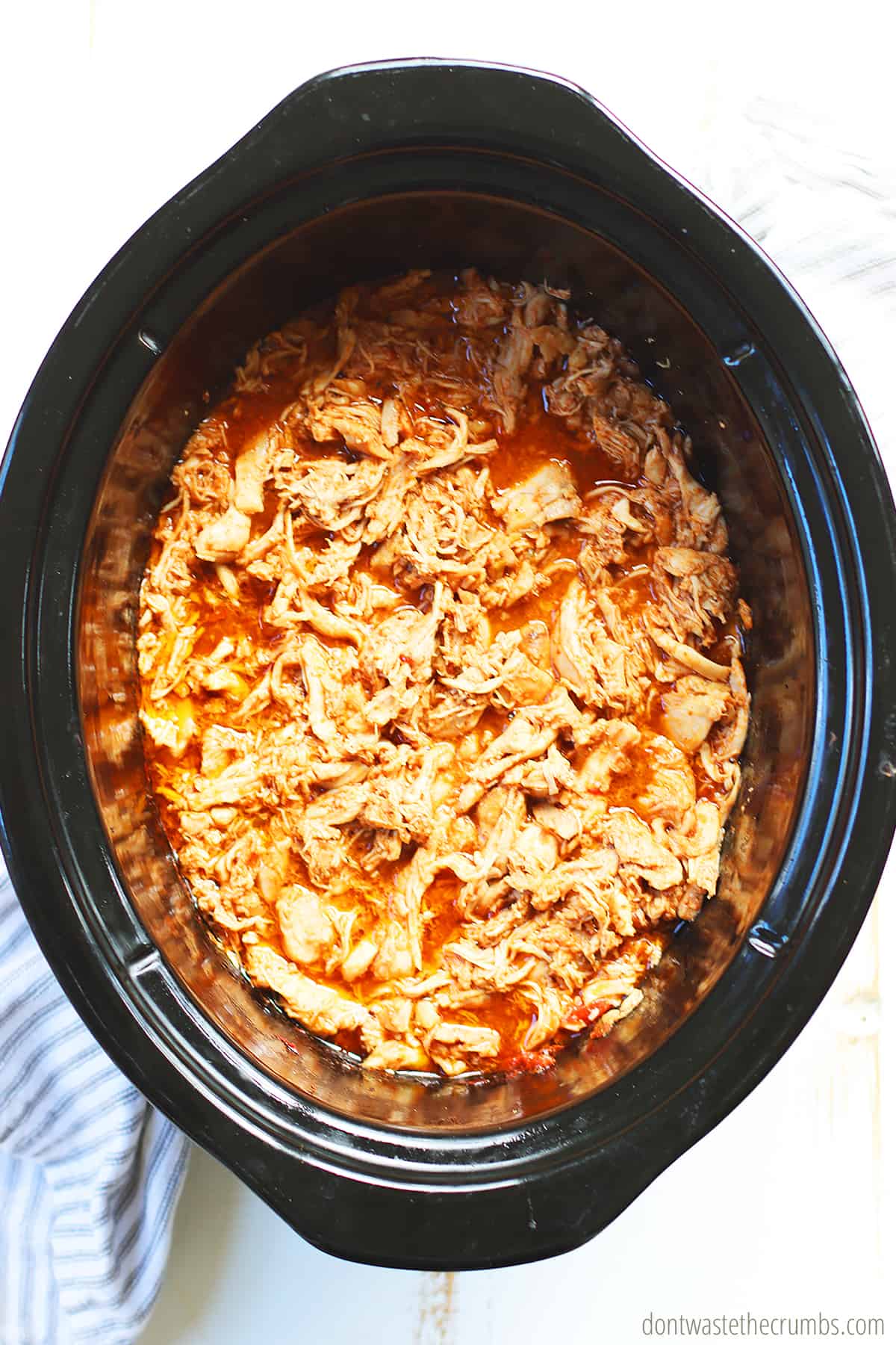 Shredded chicken in a slow cooker. This makes slow cooker chicken tacos.