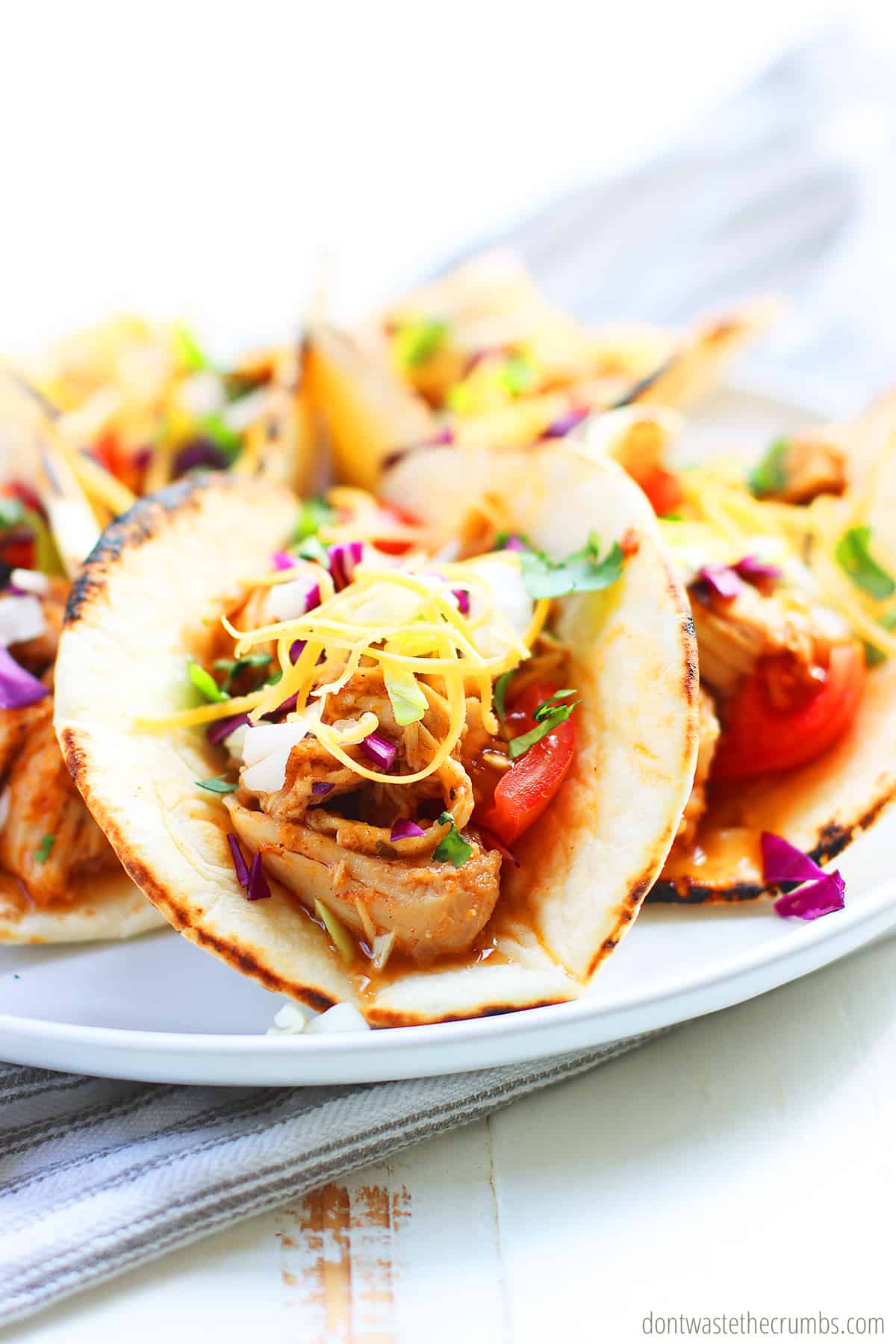 Up close view of slow cooker chicken tacos on a white plate.