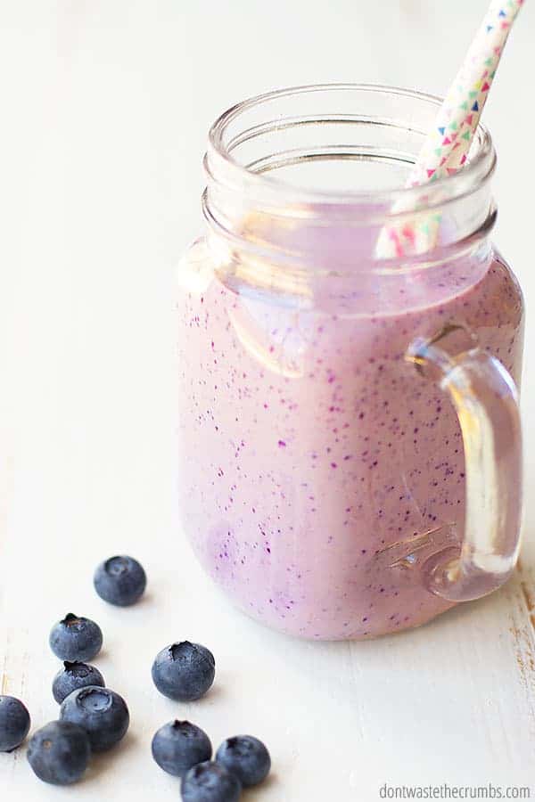 Cheesecake blueberry smoothie in a glass mason jar with a straw.
