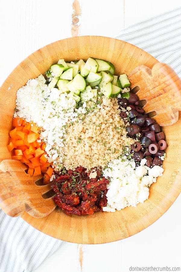 Greek quinoa salad ingredients in a big wooden bowl.