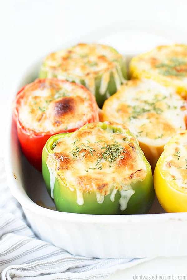 Close up view of six stuffed peppers in a white baking dish.
