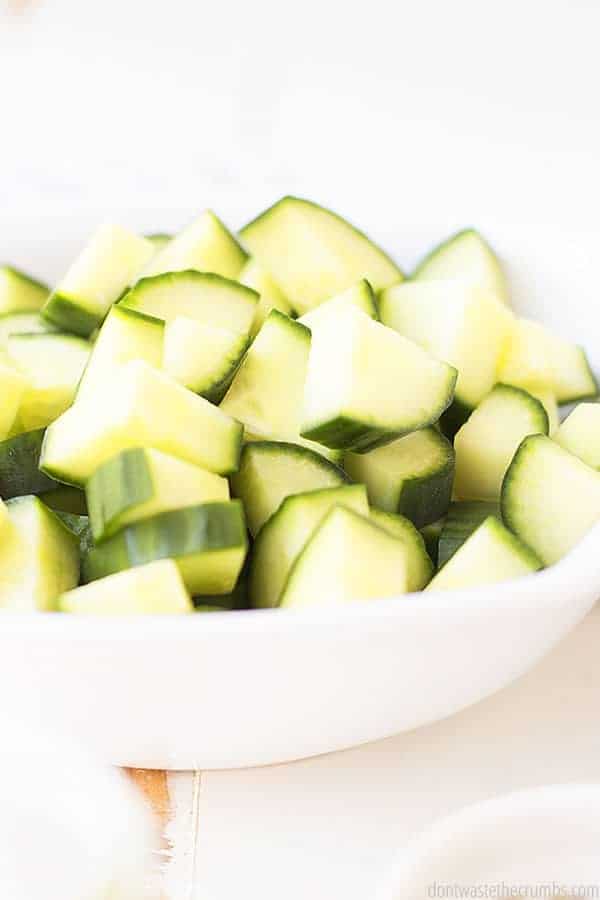 Sliced cucumbers in a white bowl.