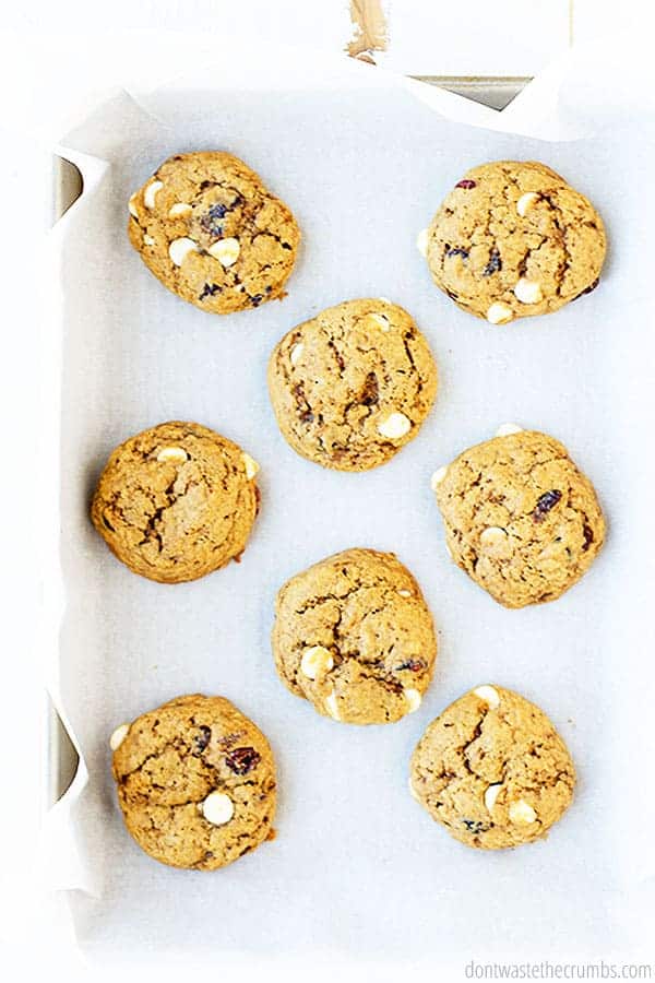 White chocolate cranberry cookies on parchment paper on a baking sheet.