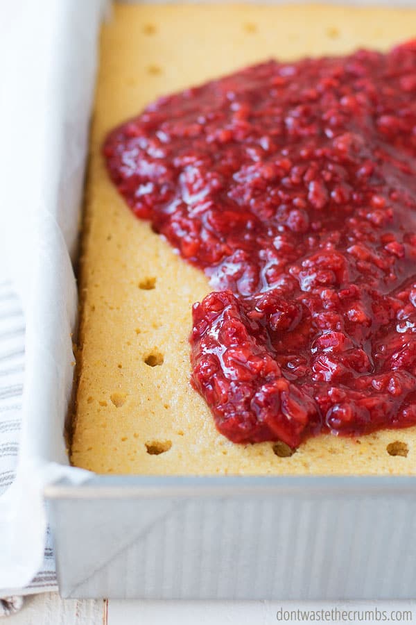 Fresh mashed berries spread on top and seeping into a homemade lemon cake.