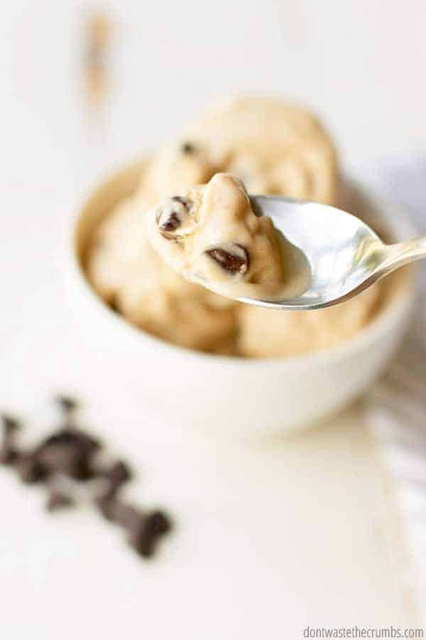 Up close view of a spoonful of homemade peanut butter chocolate chip banana ice cream. A bowl of the ice cream is in the background.