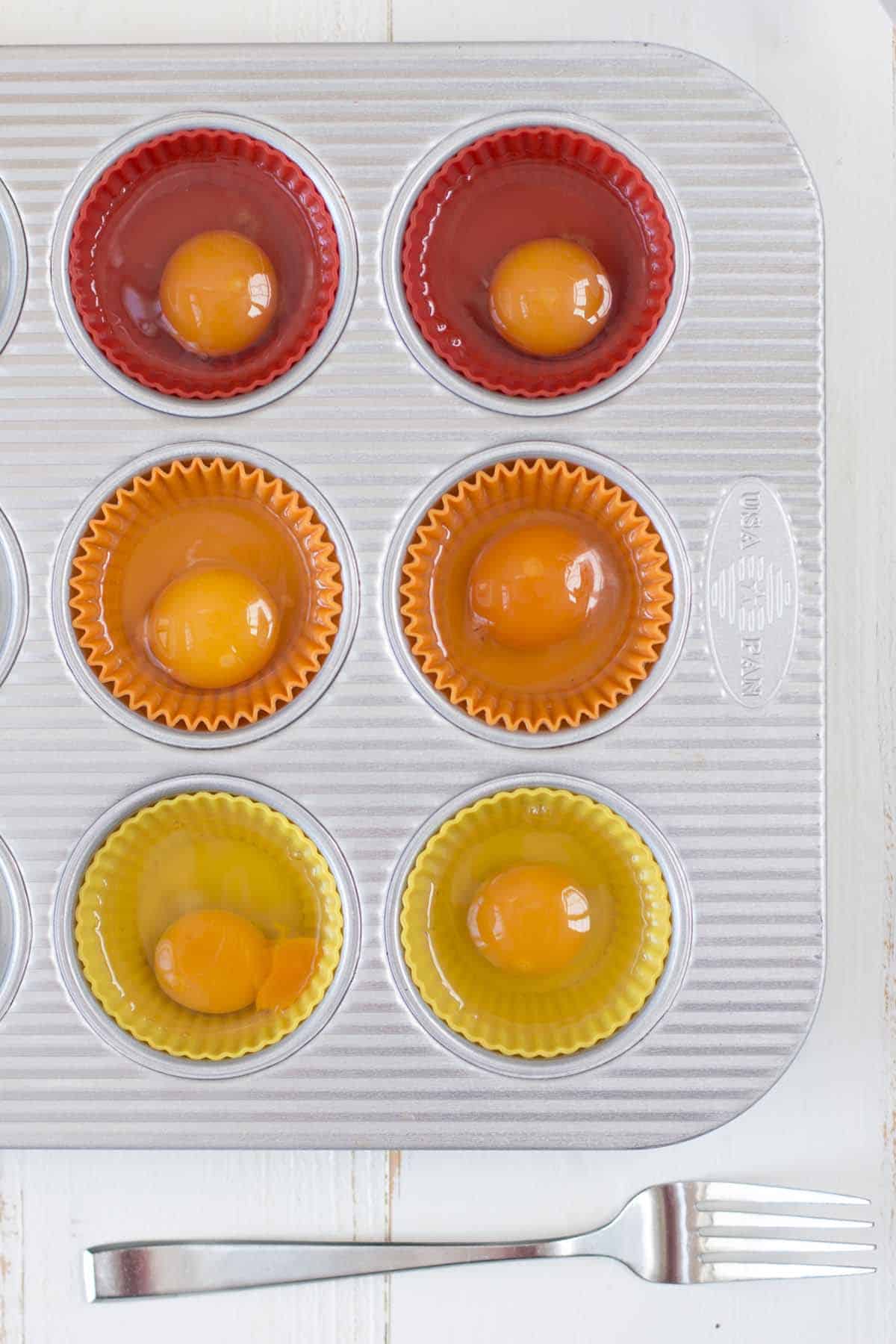 Six raw eggs in a muffin tin ready to be lightly whisked with a fork, before being frozen.