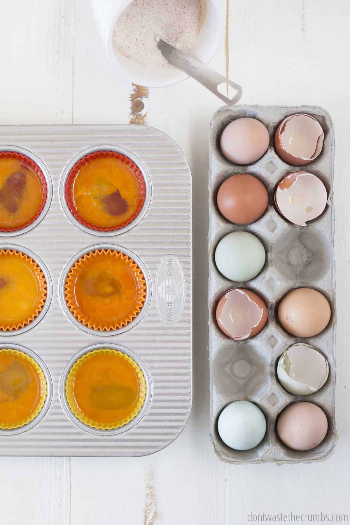 Six muffins tins filled with raw eggs and whisked - ready to be frozen.