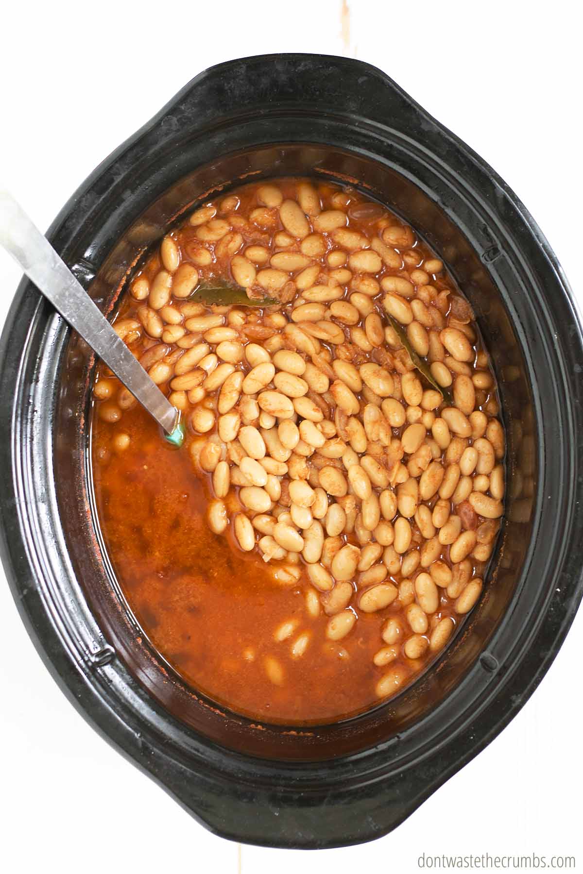 Baked beans in a slow cooker with a ladle in it