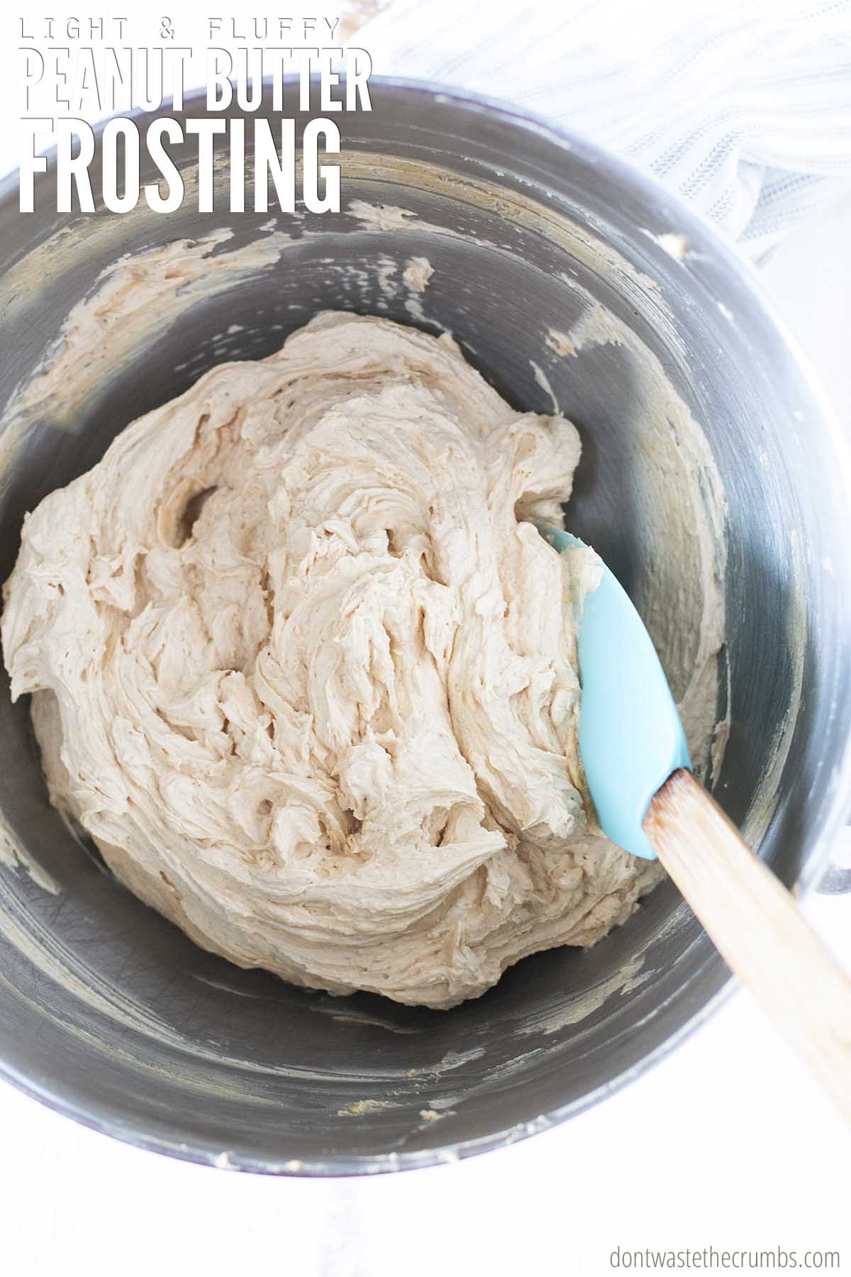 Silky smooth peanut butter frosting in a mixer bowl with a spatula. 