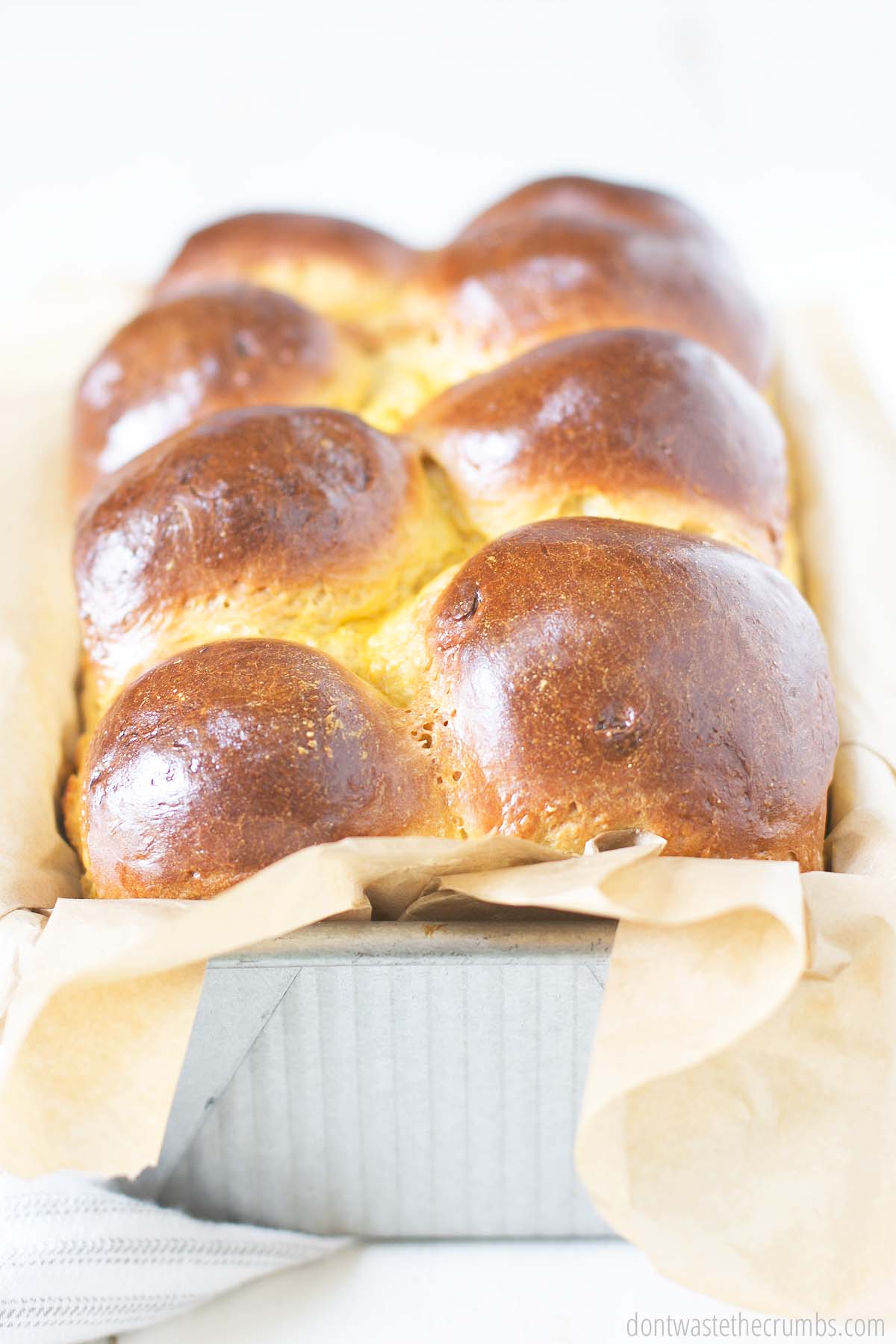 Close up view of a brioche bread in a parchment lined loaf pan.