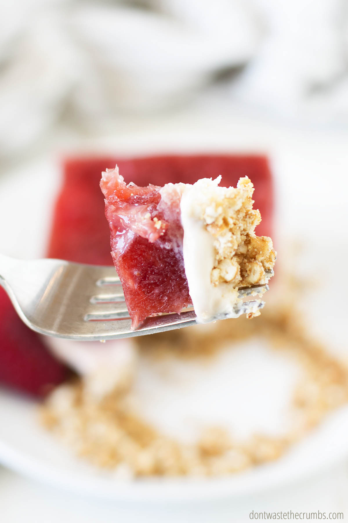 A big delicious bite of pretzel salad with strawberries on a fork.
