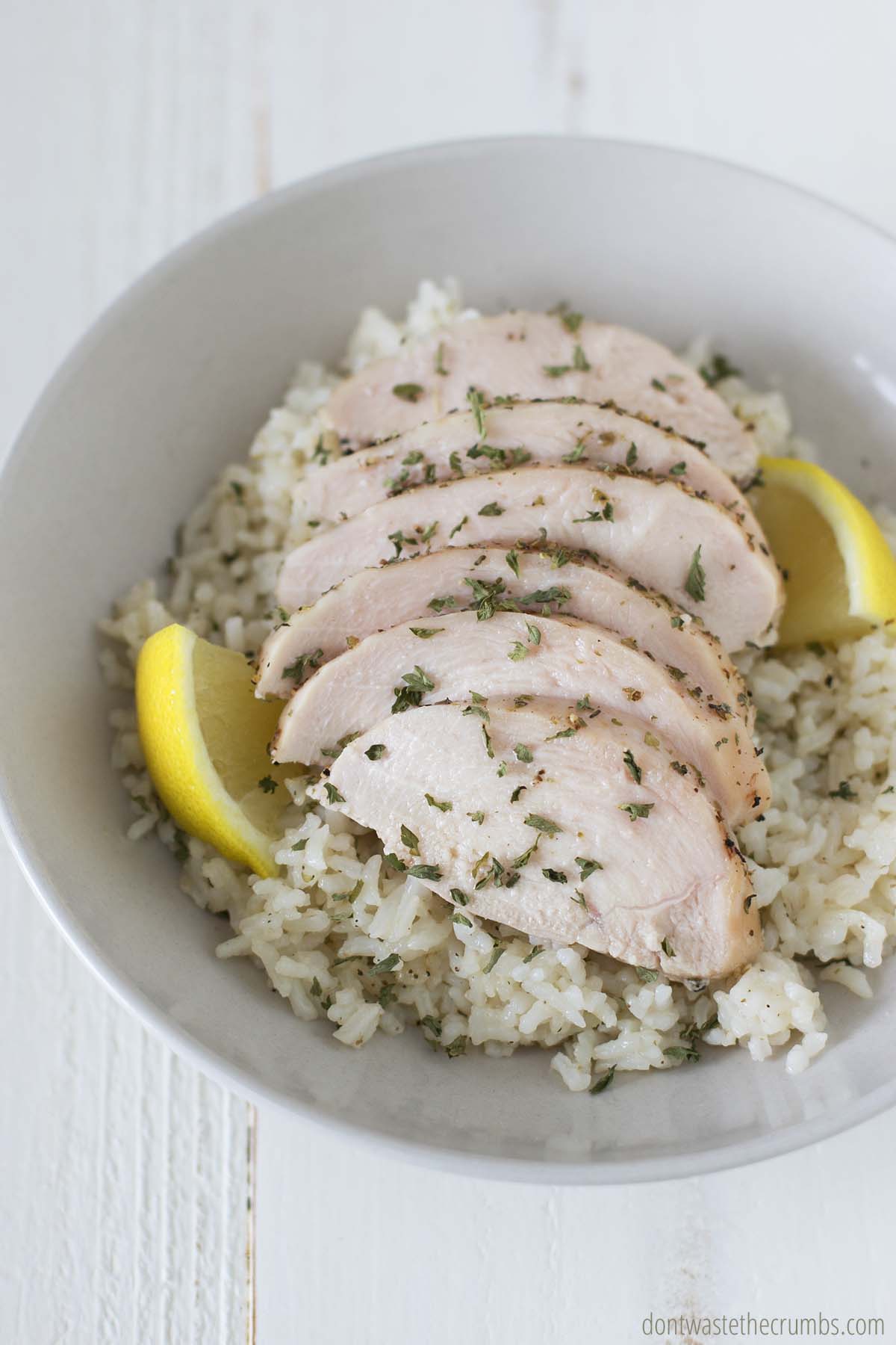 Sheet pan chicken sliced and served over rice. Garnished with fresh parsley and lemon wedges. 