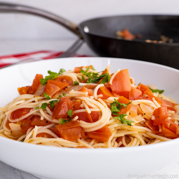 Homemade spaghetti sauce over pasta in a white bowl.
