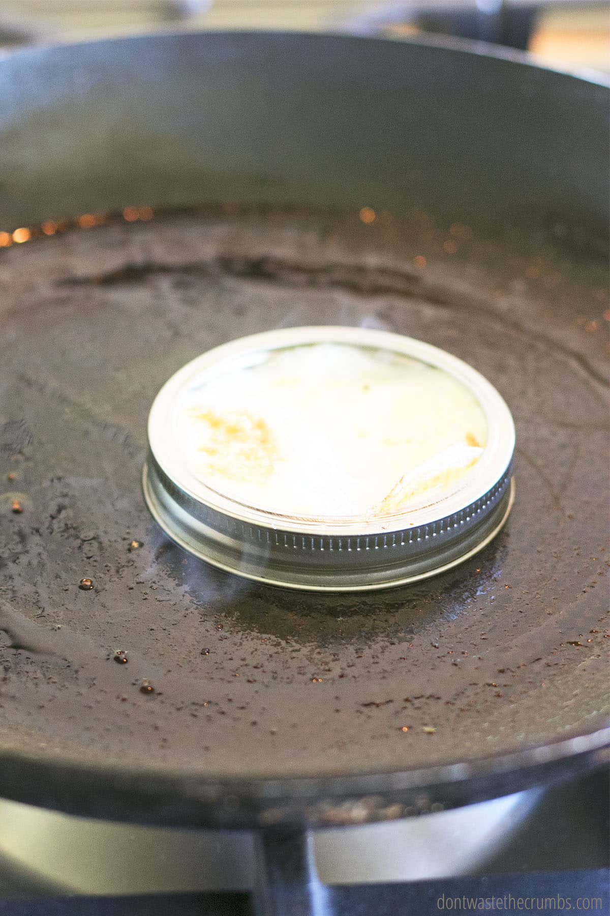 Egg cooking in a mason jar lid on a skillet.
